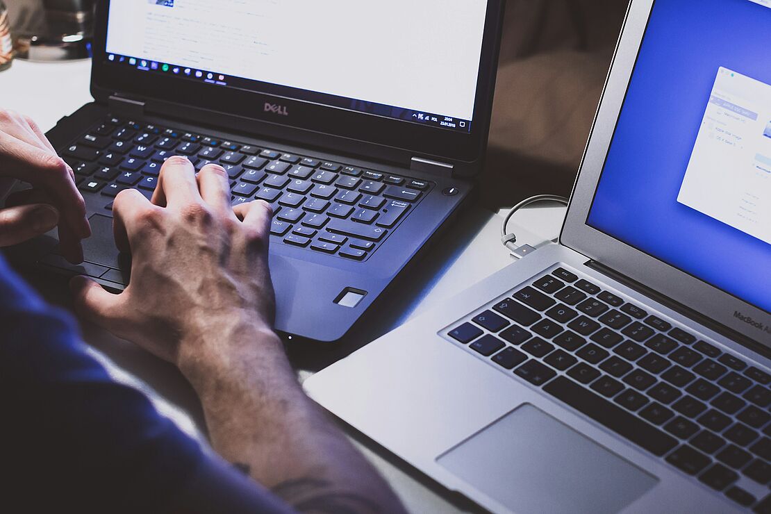 Person arbeitet an einem Laptop mit geöffneten Anwendungen und Dokumenten an einem Schreibtisch als Beispiel für digitale Steuerung und Weiterentwicklung eines Umweltmanagementsystems nach ISO 14001