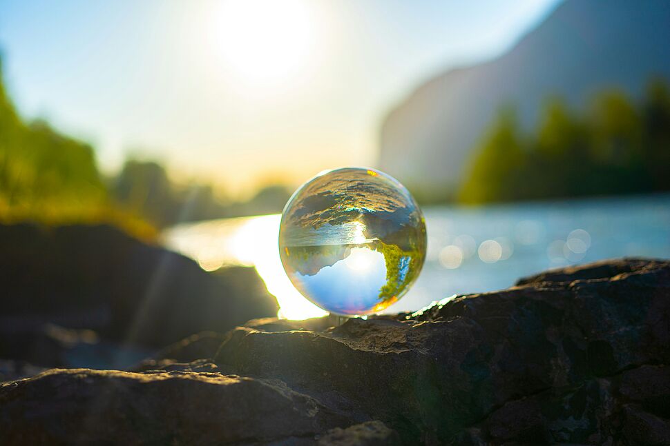 Glaskugel reflektiert die Sonne vor einem See