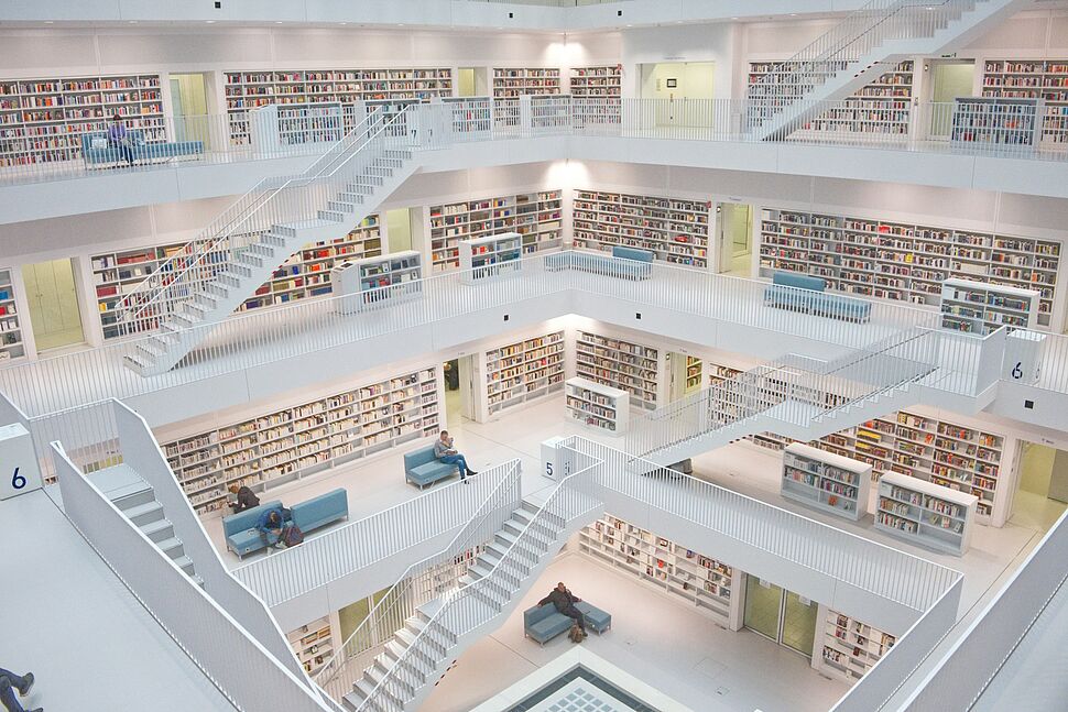 Moderne Bibliothek mit offenen Galerien, vielen Bücherregalen und festen Laufwegen als Beispiel für klar aufgebaute Prozesse