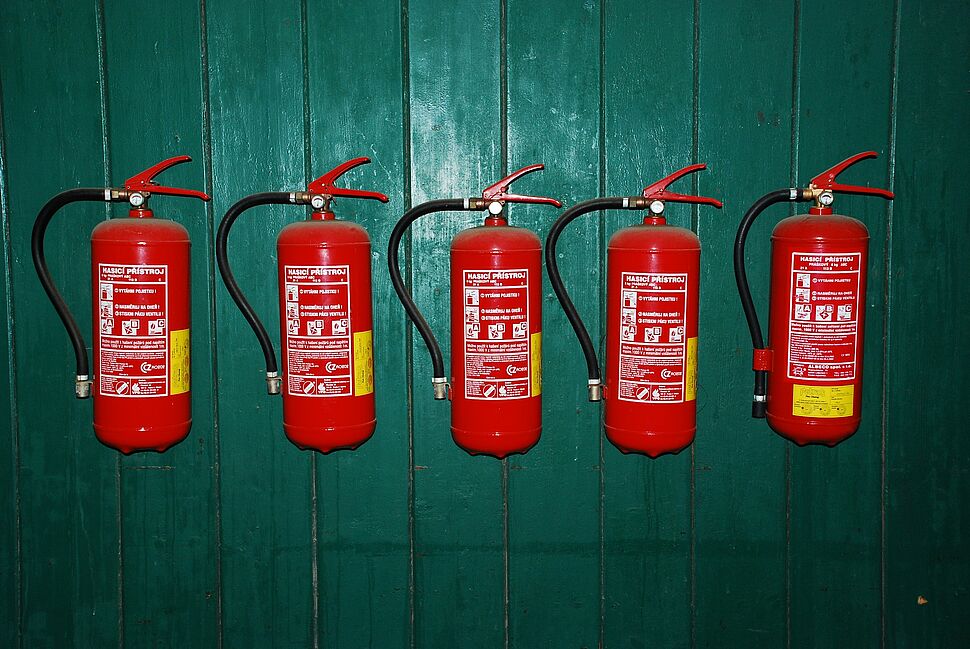 Mehrere rote Feuerlöscher als Symbol für vorbeugenden Brandschutz und die Ausbildung zum Brandschutzbeauftragten