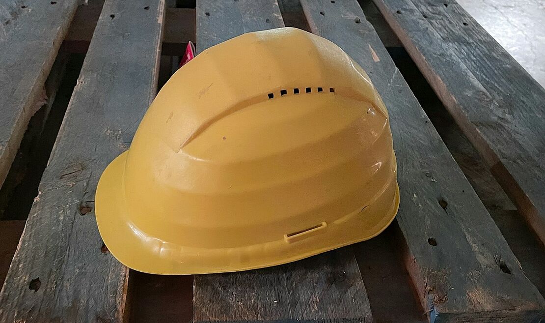 Gelber Schutzhelm als Bestandteil der persönlichen Schutzausrüstung (PSA) auf einer Baustelle – Symbol für Arbeitsschutz durch Sicherheitsbeauftragte