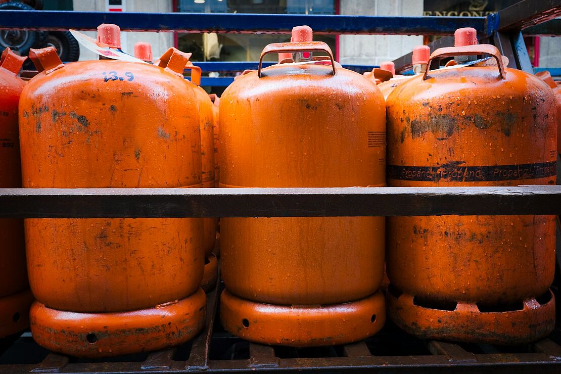 Große orangene Gasbehälter stehen nebeneinander in einer Lagerumgebung als Beispiel für die Aufbewahrung und Kennzeichnung von Gefahrgut