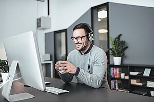 Mann sitzt am PC und nimmt an einer Online-Schulung teil