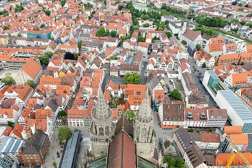 Panoramaaufnahme der Stadt Ulm mit dem Ulmer Münster, roten Dächern und der historischen Innenstadt.