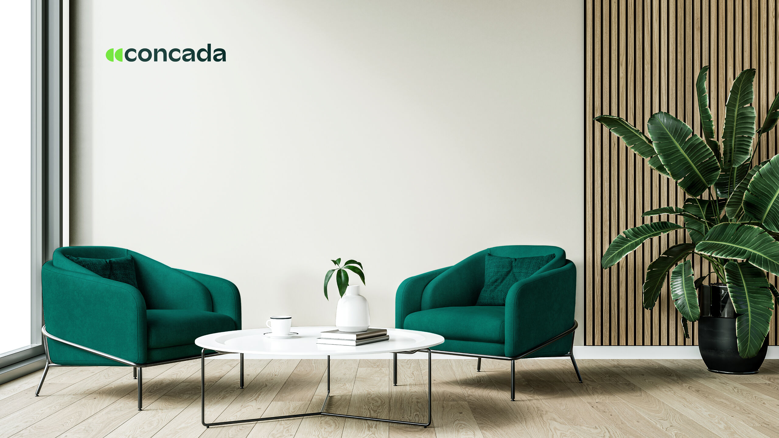 Modern eingerichteter Sitzbereich mit zwei grünen Sesseln, einem runden weißen Couchtisch mit Dekoobjekten sowie einer großen grünen Zimmerpflanze; an der Wand links befindet sich das concada‑Logo