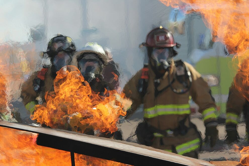 Ein Gruppe Feuerwehrmänner stehen vor einem Feuer