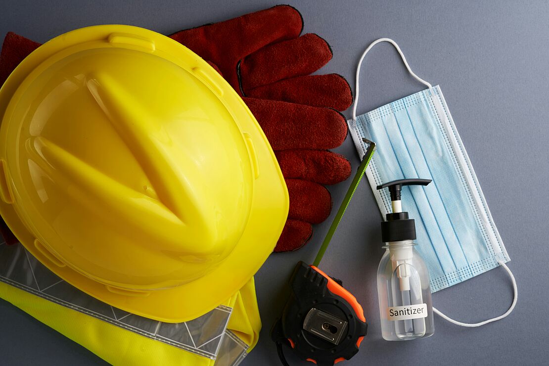 Arbeits- und Gesundheitsschutz in der Praxis: Schutzhelm, Warnweste, Handschuhe, Atemschutzmaske und Desinfektionsmittel als typische Elemente der Fachkraft für Arbeitssicherheit