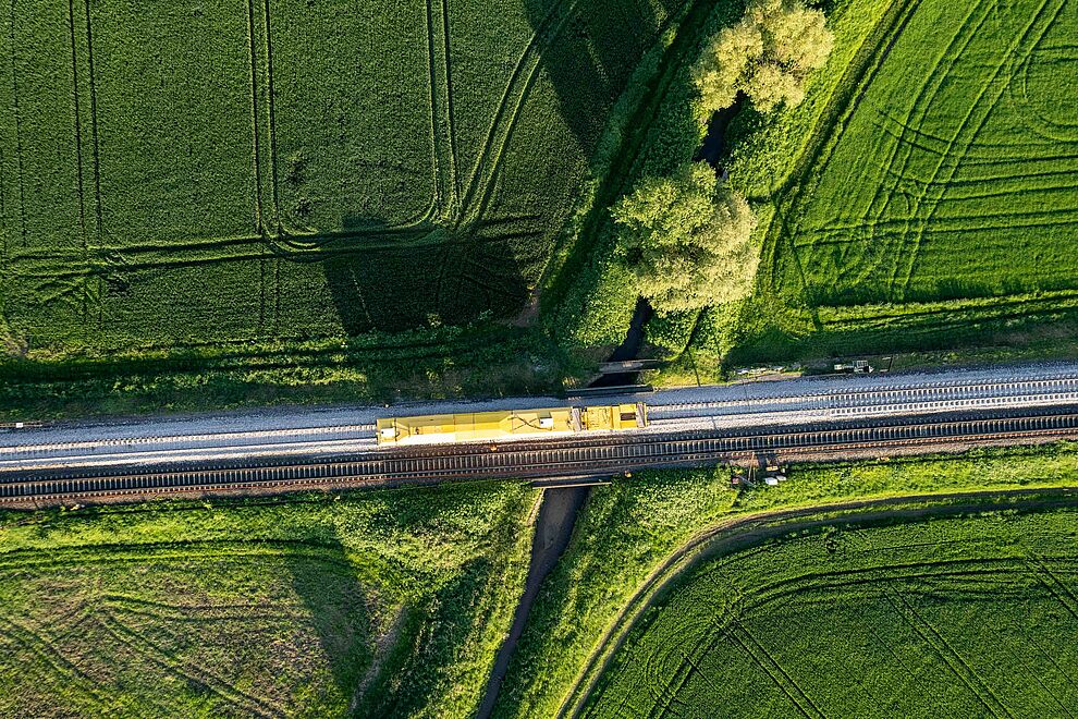 Ein Zug fährt durch grüne Wiesen und Felder