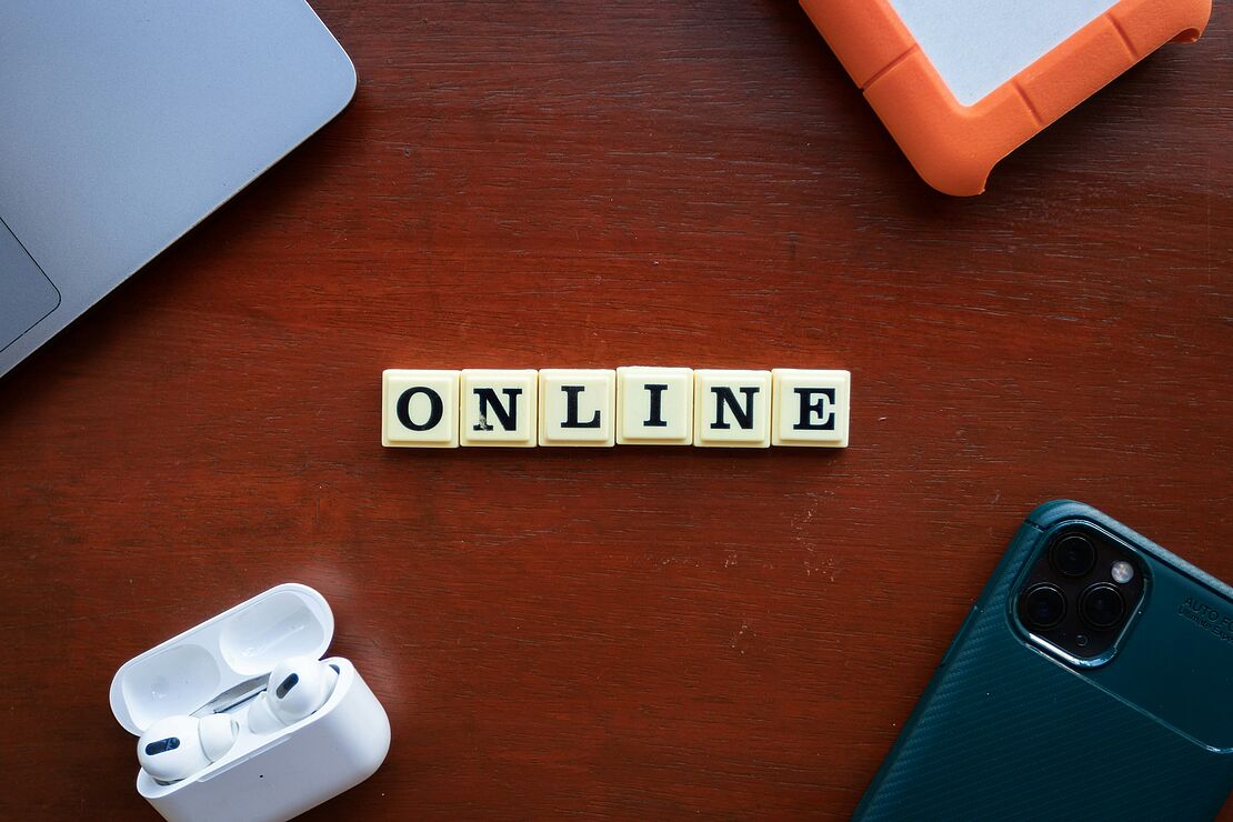 Schreibtisch mit Laptop, Smartphone, Kopfhörern und Notizblock als Beispiel für digitales Arbeiten und moderne Online‑Weiterbildung