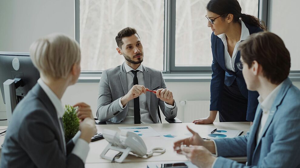 Vier Personen besprechen Unterlagen und Diagramme an einem Tisch zur Planung interner Audits im Qualitäts- und Umweltmanagement