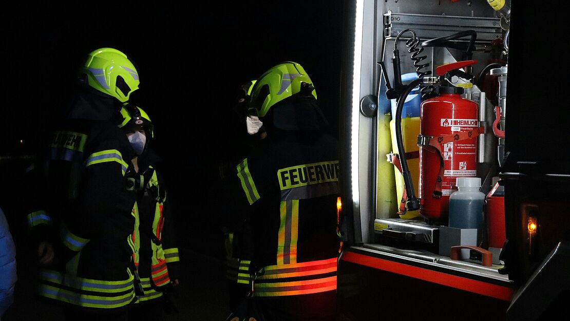 Personen mit Feuerwehrschutzkleidung vor einer technischen Anlage mit Brandbekämpfungsausrüstung als Beispiel für Brandschutzmaßnahmen in industrieller Umgebung