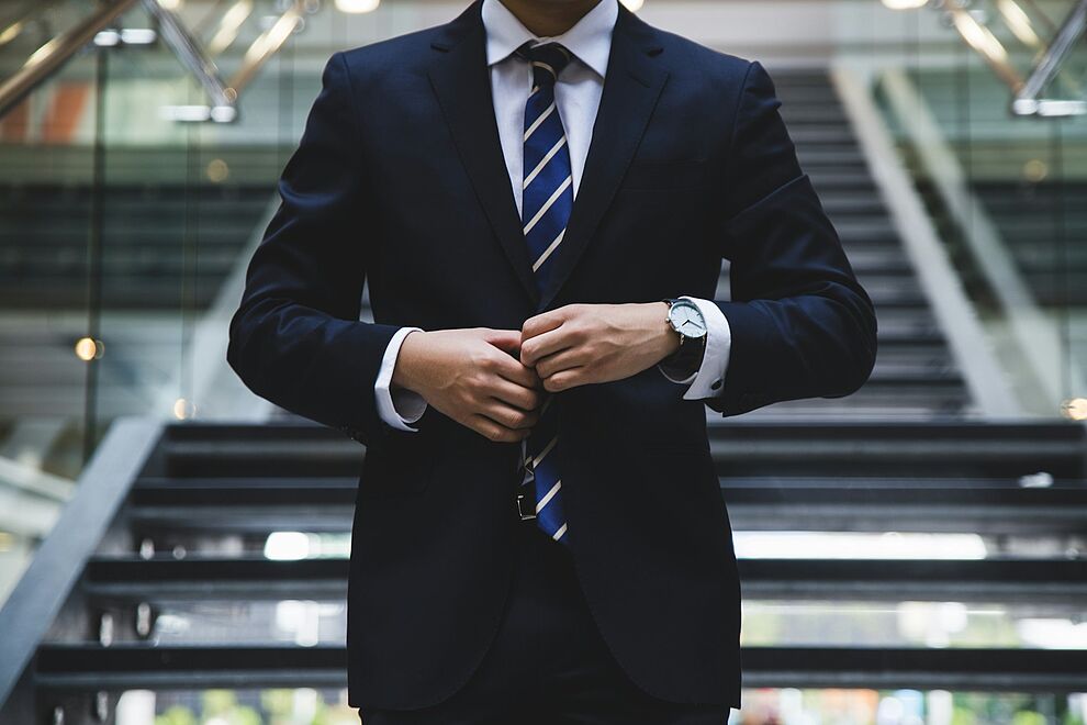 Person in Businesskleidung steht in einem modernen Gebäude als Symbol für Verantwortung und Haftung von Führungskräften im Arbeits- und Umweltschutz.