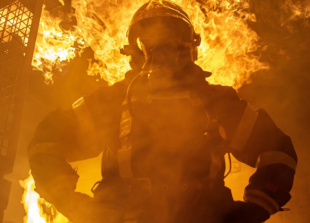 Einsatzkraft mit Atemschutz vor Flammen als Symbol für professionellen Brandschutz und die Qualifikation zum Brandschutzbeauftragten