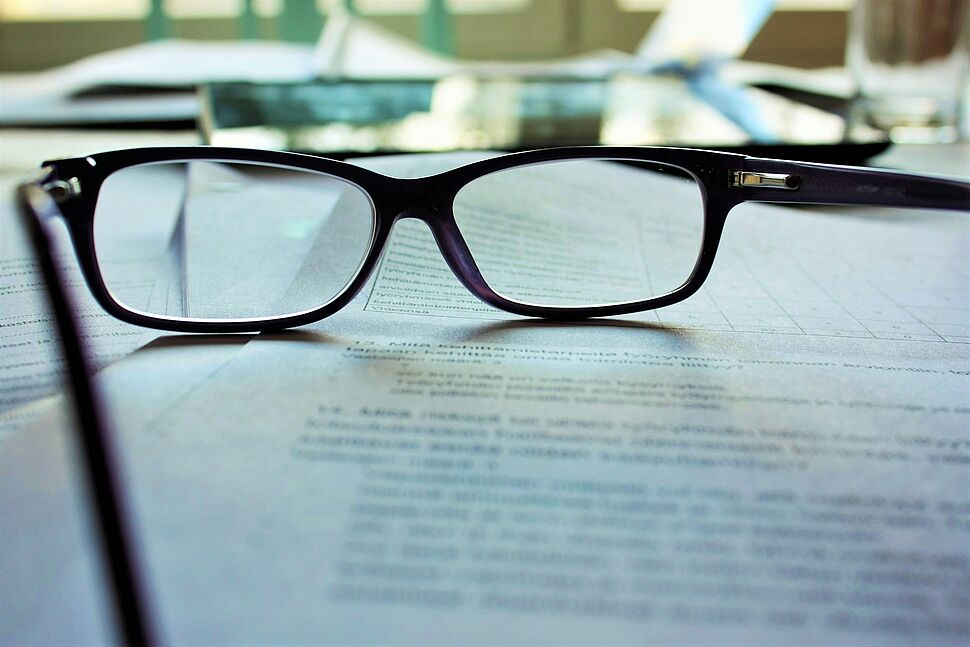 Brille liegt auf Tisch und Papier